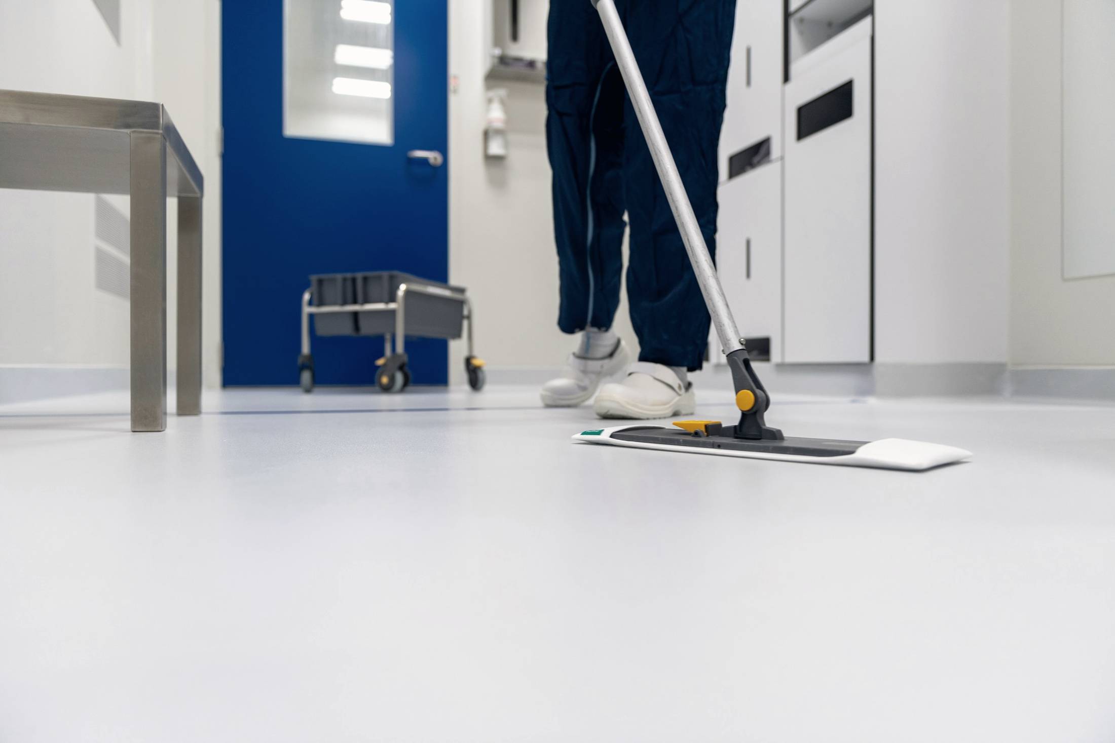 Cleaner mopping the floor of a clinical corridor