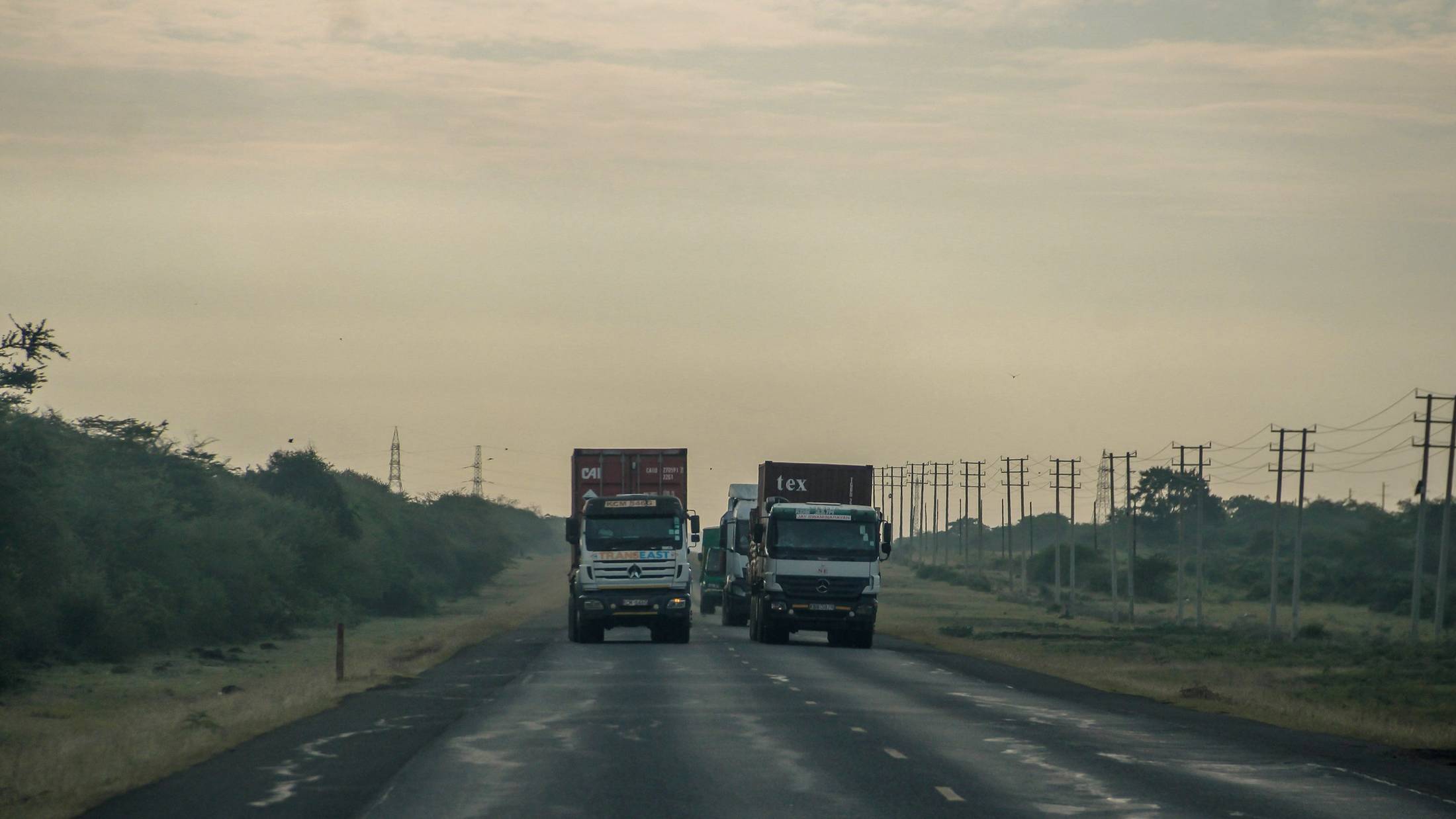 Cargo trucks travelling along a highway through open countryside
